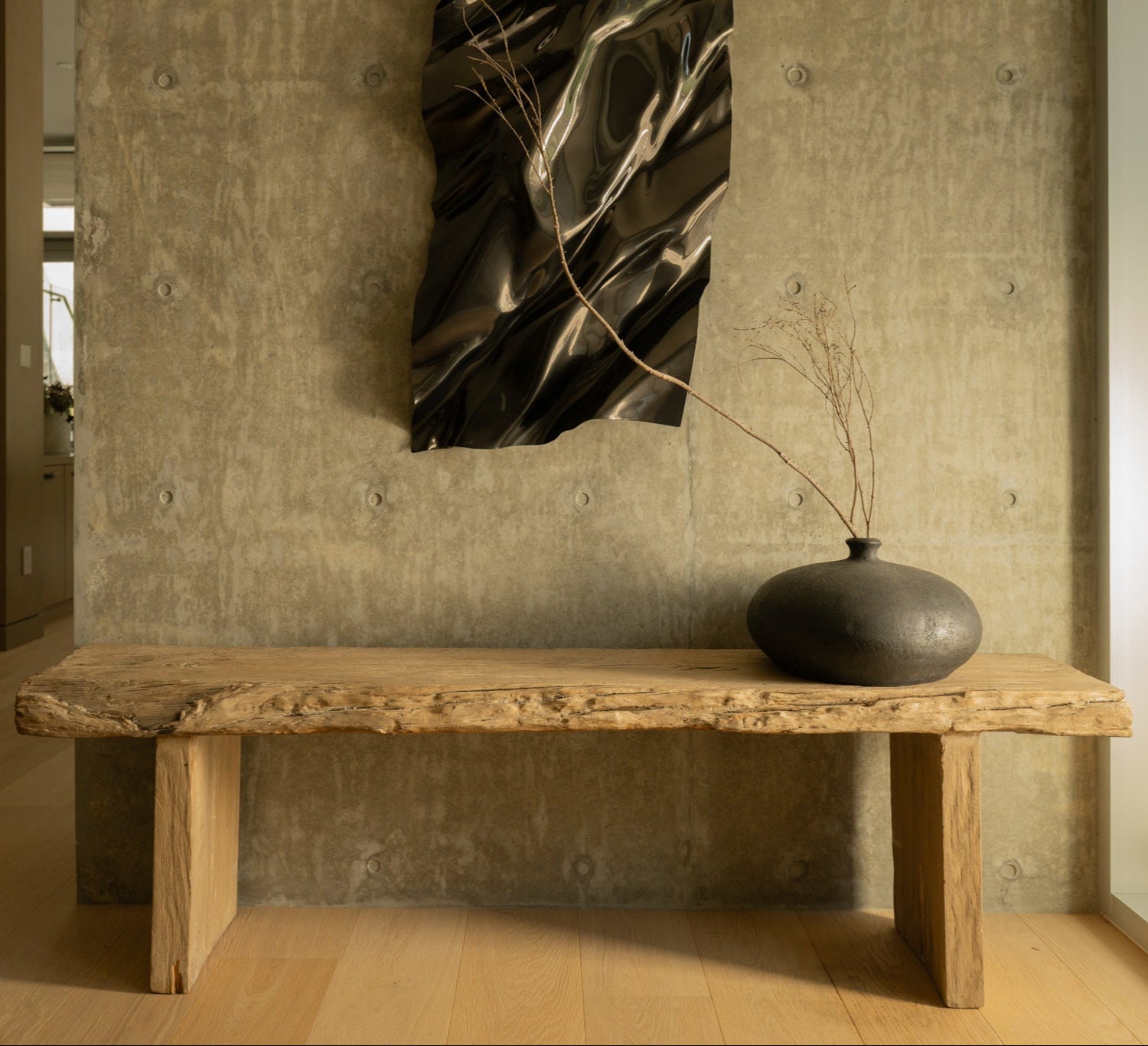 Wooden bench in a room with a textured wall and abstract art.